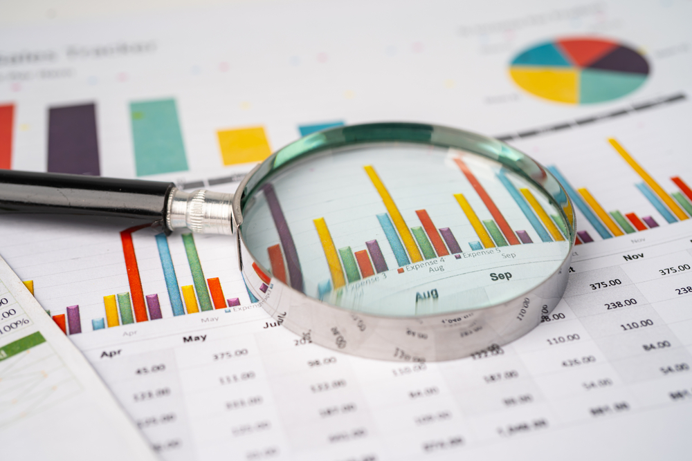 A magnifying glass over a series of bar graphs