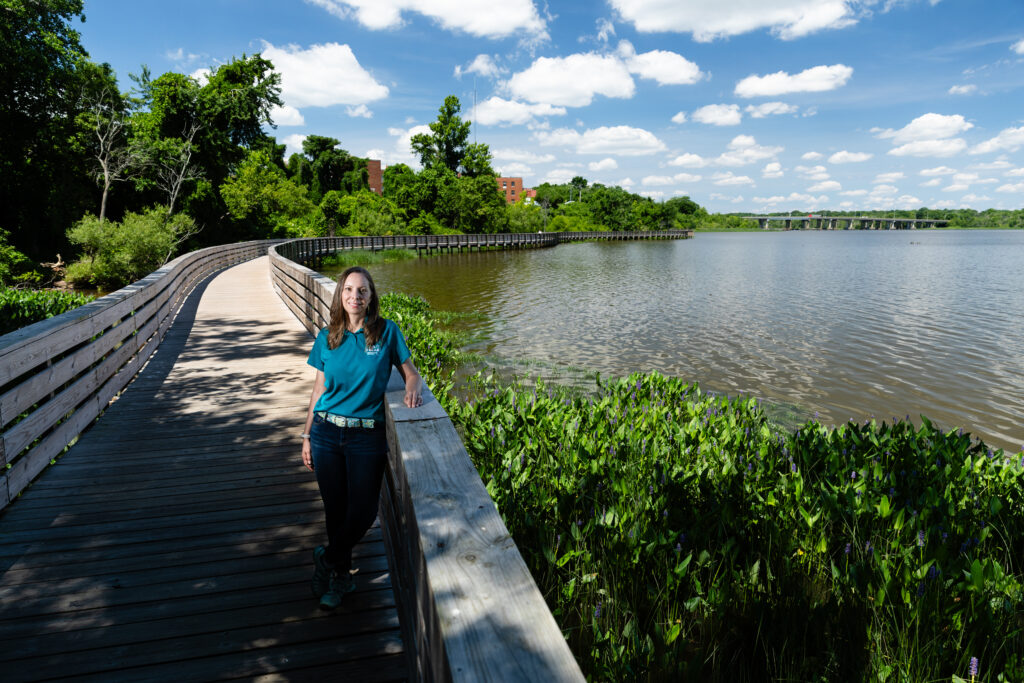 Heather Barrar of Friends of the Lower Appomattox River (FOLAR) poses at the Riverwalk in Hopewell, Va., on June 10, 2022. The 1,736-foot wooden boardwalk, which opened in 2019, is part of FOLAR's Appomattox River Trail and is a keystone in the organization's efforts to increase public access to the river. (Photo by Will Parson/Chesapeake Bay Program)